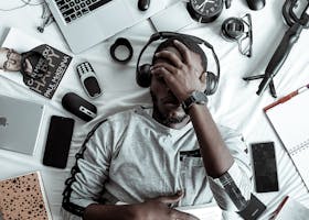 pexels-photo-3345882-3345882 A young man lying on a bed surrounded by modern gadgets, books, and tech devices, illustrating digital lifestyle.